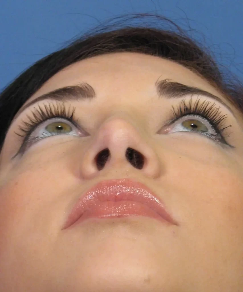 Close-up of a person looking upward, showing their nostrils, lips, eyes, and makeup.