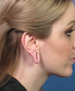 Profile of a person with stretched earlobes, showing smooth skin and neatly pinned hair.