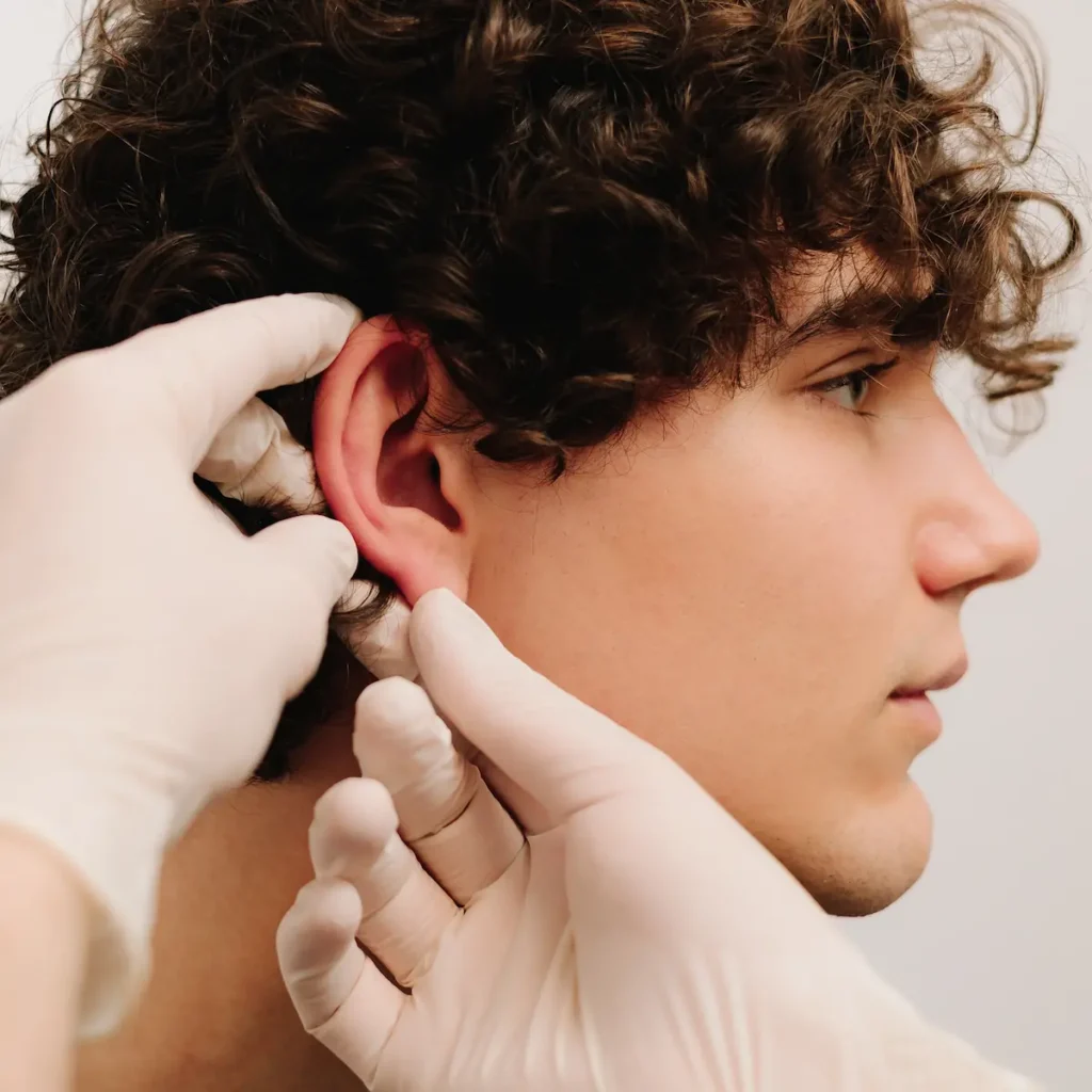 plastic surgeon examining patient's ear during otoplasty consultation